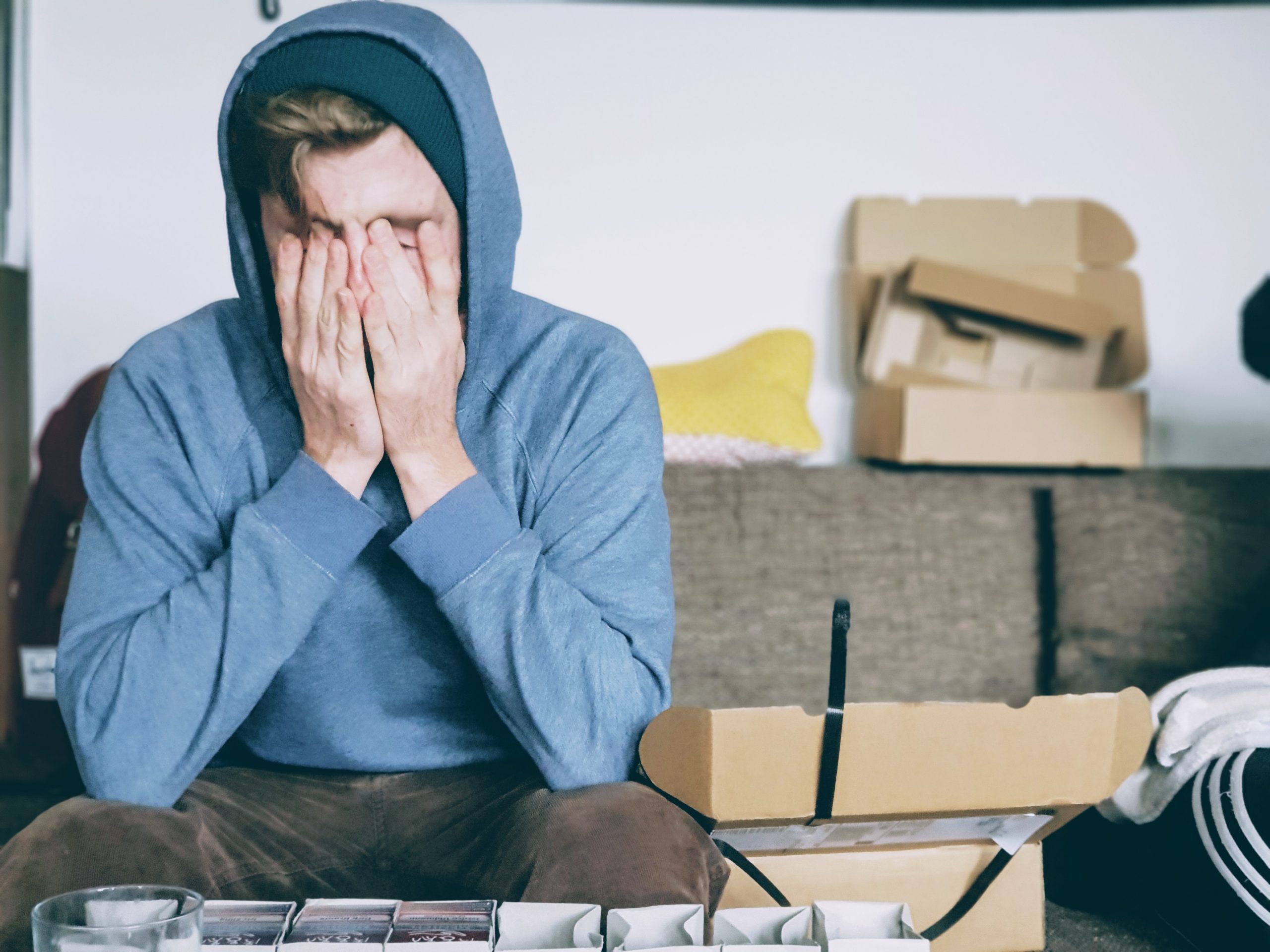 Man with his hood up and head in his hands